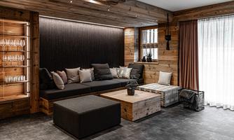 A modern living room with wooden paneling and a cozy seating area. Large windows let in plenty of light and create an inviting atmosphere.