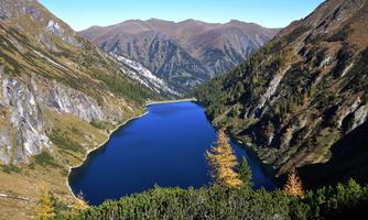 A clear mountain lake surrounded by tall mountains and beautiful trees. The landscape is calm and breathtaking.