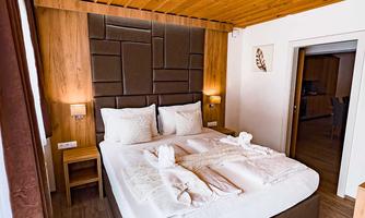 A cozy bedroom with a large bed and warm wooden elements. The atmosphere is inviting and designed in a modern style.