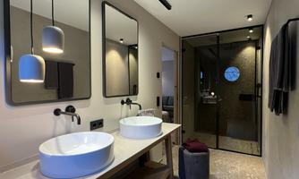 A modern bathroom with two sinks and large mirrors. The glass shower partition and the contemporary style create an elegant atmosphere.