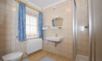 A simple bathroom with bright tiles and blue curtains. There is a shower, a sink, and a toilet.