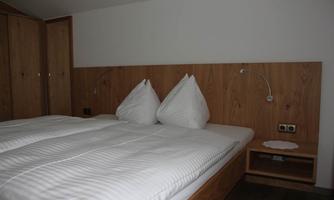 A cozy bedroom with a double bed and wooden furniture. The pillows are arranged in a distinctive shape.