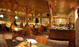 A cozy restaurant with wooden decor and warm light. The tables are neatly set and the atmosphere is inviting.