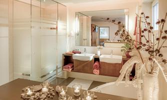 A modern bathroom with two sinks and large mirrors. Decorative candles and towels create a relaxed atmosphere.