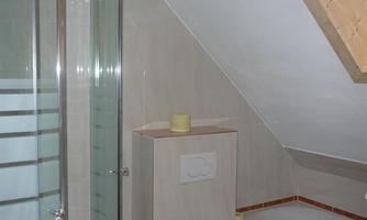 A modern bathroom with a shower and bathtub. The walls are light, and there are wooden details in the ceiling area.