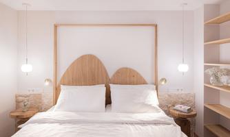 A modern bedroom with a large bed and a wooden headboard. The walls are painted in soft colors, and there are stylish nightstands with small lamps.