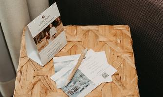 A table with a woven basket and several cards on it. A pen lies next to the cards, which present information and images.