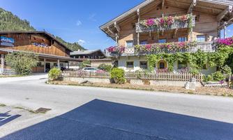 A picturesque mountain village with traditional wooden houses and colorful flowers. The sky is clear and the landscape is surrounded by green mountains.
