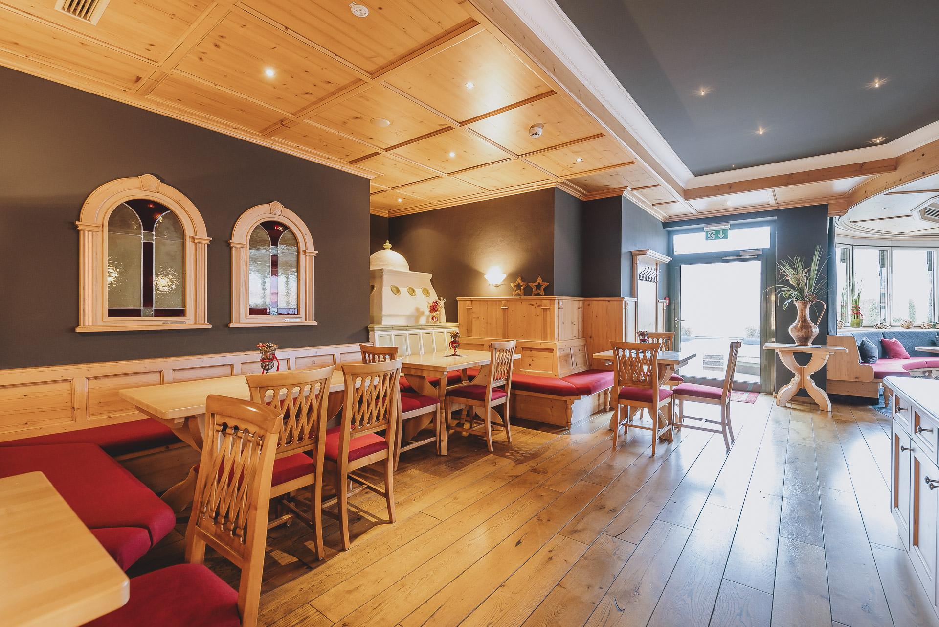A cozy restaurant with wooden furniture and a warm, inviting atmosphere. There are comfortable seating options and large windows that let in plenty of daylight.