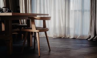 A modern wooden dining table with an elegant seating area. Soft light streams through the curtains, creating an inviting atmosphere.