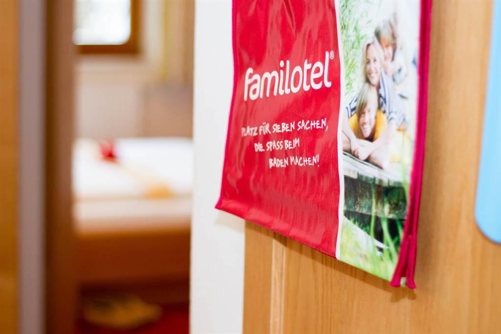 A red Familiotel sign hangs on the door. It features images of happy children and families.