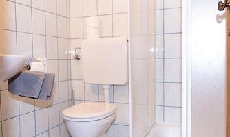 A small bathroom with bright tiles. It contains a shower, a toilet, and a sink.