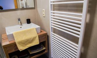 A modern bathroom with an elegant sink and a towel holder. A yellow towel adds a colorful accent.