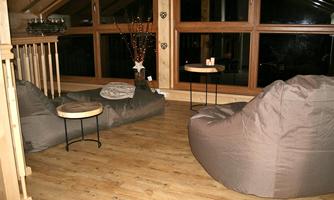 A cozy room with fabric bean bags and small tables. The room has large windows with a view outside.