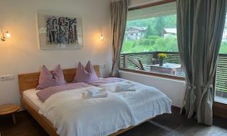 A cozy bedroom with a large bed and a beautiful view. Bright curtains and a modern style create an inviting atmosphere.