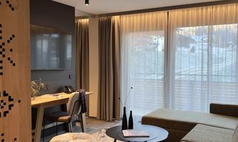 A modern apartment with a cozy living area. The space is bright and inviting, featuring large windows and stylish furniture.
