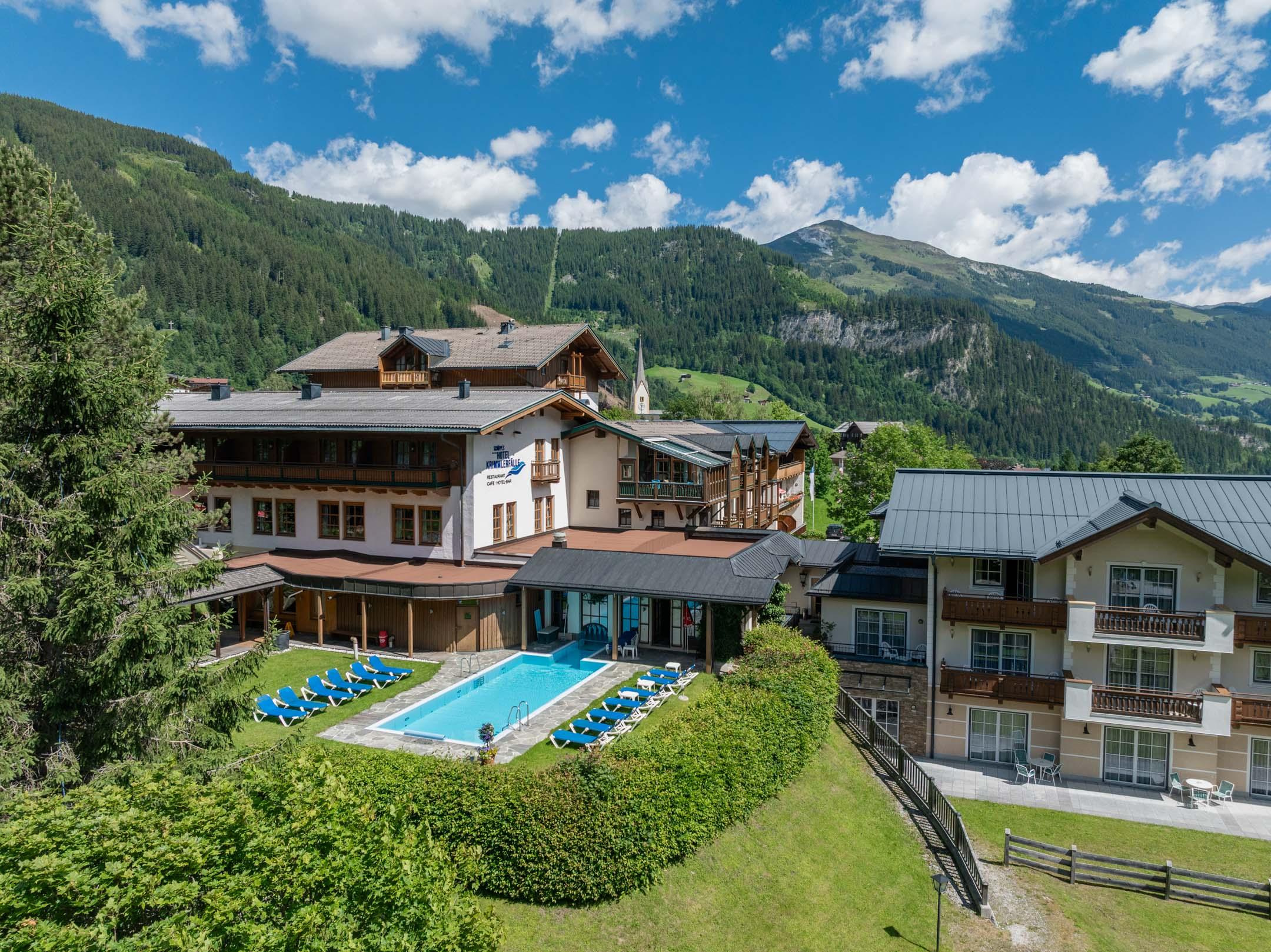 A picturesque hotel in the mountains with a pool and outdoor loungers.  
Surrounded by green nature and beautiful scenery.