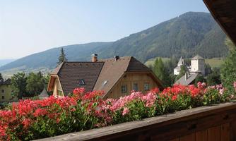 A picturesque view of a village with charming houses and blooming flowers. In the background, gentle hills and forests stretch out.