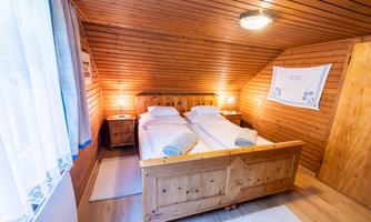 A cozy bedroom with wood paneling and two beds. Soft towels are ready, and the lighting creates a warm atmosphere.