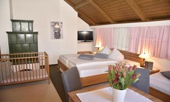 A comfortable, cozy room with 2 sleeping areas, a connecting door, a large double bed, 1 single bed, 1 crib, 1 table with 4 chairs, cable television, 1 wardrobe, as well as 1 sofa bed with a bench, bedside table, and shower WC.