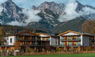 Modern buildings in a picturesque mountain landscape. The clouds surround the majestic mountains in the background.