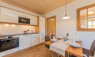 Modern kitchen with elegant furniture and wooden floor. The table is nicely set and invites you to eat.