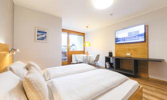 A modern studio with a double bed and a cozy dining area. Large windows provide plenty of daylight and a bright atmosphere.