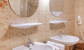 A modern bathroom with two sinks and round mirrors. The walls are decorated with tiles in soft colors.