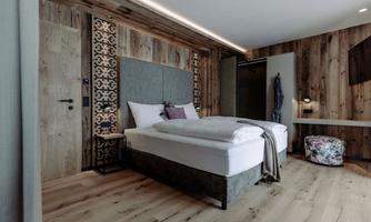 A modern bedroom with a large bed and wooden paneling. There is a cozy atmosphere and stylish furniture.