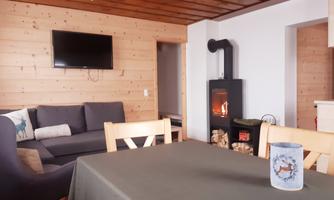 A cozy living space with a couch, a table, and a fireplace. The wood paneling creates a warm atmosphere.