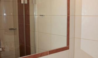 A modern bathroom with a large mirror and a bathtub. Towels and toothbrushes are neatly arranged.