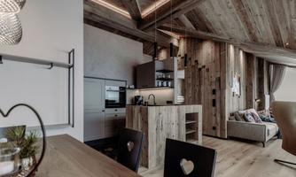 A modern apartment with wooden paneling and an open kitchen. The space is bright and cozily furnished.