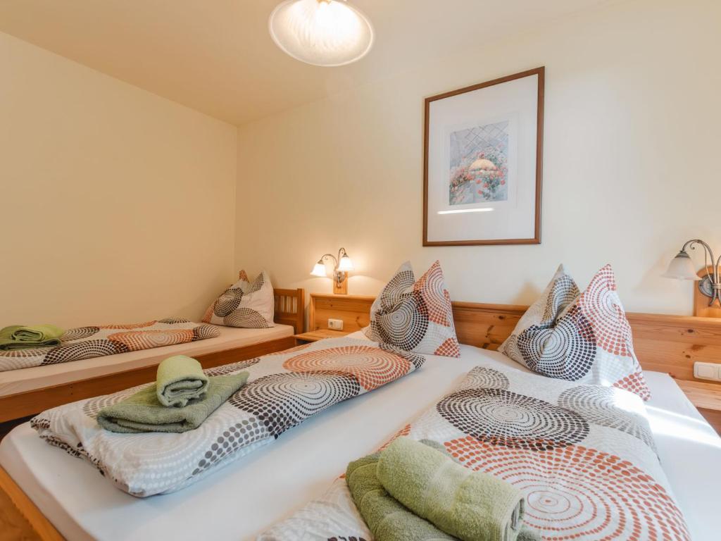 <p>Cozy bedroom with a double bed and a single bed, colorful bedding, rolled-up towels and warm light. Above the beds, a framed picture hangs on the wall.</p>