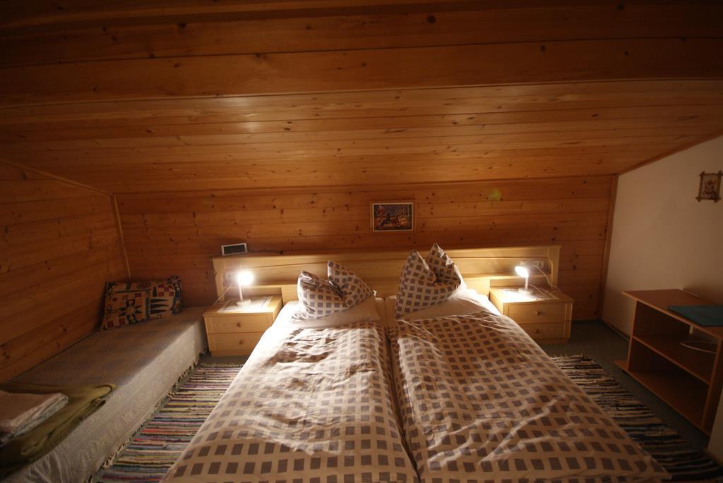 A cozy bedroom with wooden paneling and two single beds. The room is well-lit and offers an inviting atmosphere.