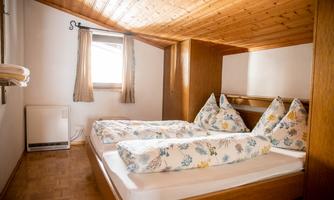 A cozy bedroom with two beds and pillows in the shape of triangles. Bright walls and wooden paneling create a warm atmosphere.