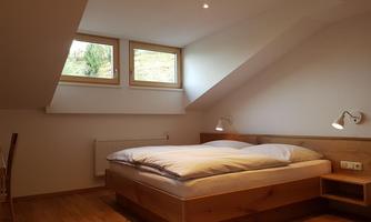 A cozy bedroom with a large bed and wooden furniture. It has skylights that let in a lot of daylight.