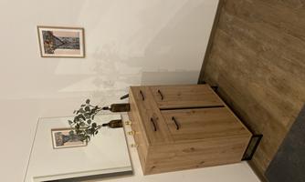 A modern entrance area with a wooden cabinet and a mirror. A piece of artwork hangs on the wall, and a vase with plants is on the cabinet.