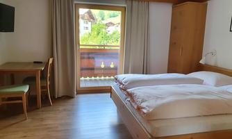 A cozy room with a double bed and a small table. Large windows offer a beautiful view outside.