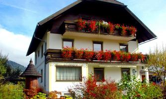 A pretty house with flower boxes and traditional architecture. The surroundings are green and inviting.