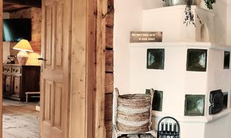 An inviting room with a wooden door and rustic decor. In the corner, firewood is stacked and decorative elements hang from the wall.
