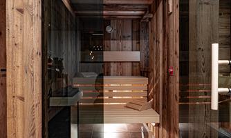 A modern wellness area with wooden details and a clear glass front. The sauna is designed in a cozy atmosphere with harmonious materials.