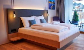 A modern bedroom with a large, comfortable bed. Large windows offer a view of the outdoors.