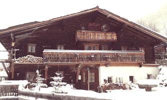 A cozy mountain cabin in winter, surrounded by snow. The balcony and wooden details give it rustic charm.
