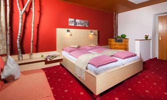 A modern bedroom with a large bed and red walls. The room has a cozy atmosphere and is decorated with stylish furniture.