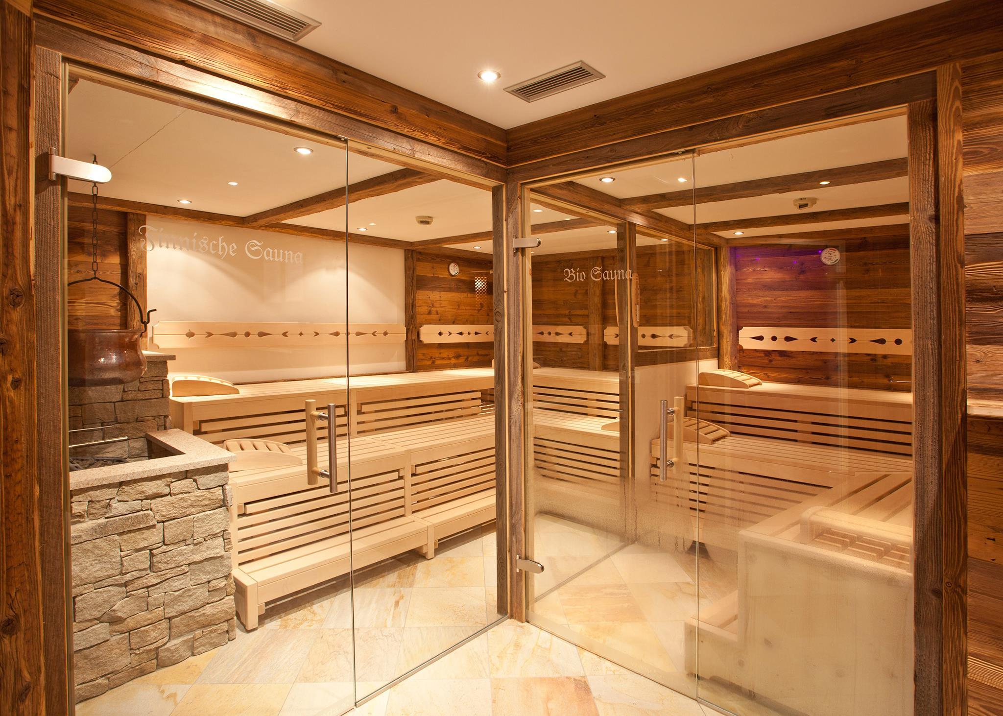A modern wellness sauna area with wooden paneling and glass walls. The seats are made of wood, and the room appears inviting and relaxing.