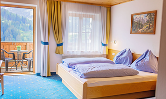 A cozy hotel room with a double bed and two pillows. The balcony offers a view of the mountains and invites you to relax.