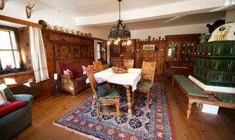 A traditional cozy dining room with wooden paneling and a large table in the center. The furniture is rustic and there is a colorful rug on the floor.