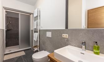 A modern bathroom with clean lines. It includes a shower, a sink, and underfloor heating.