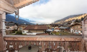 A view from a balcony of a picturesque village in the mountains. The clouds are partially visible and the landscape is calm and inviting.