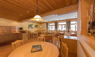 A bright and inviting restaurant with wooden paneling. The tables are neatly set and large windows let in plenty of light.